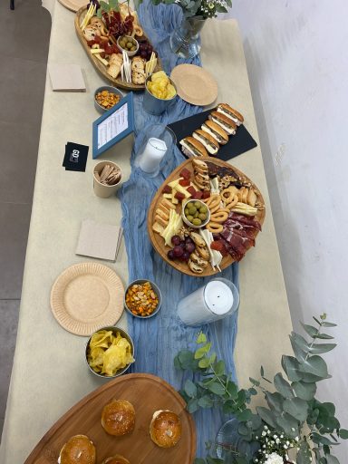 Mesa de bienvenida para bautizo con surtido de quesos, jamón reserva y morcilla artesana en evento fuera del salón